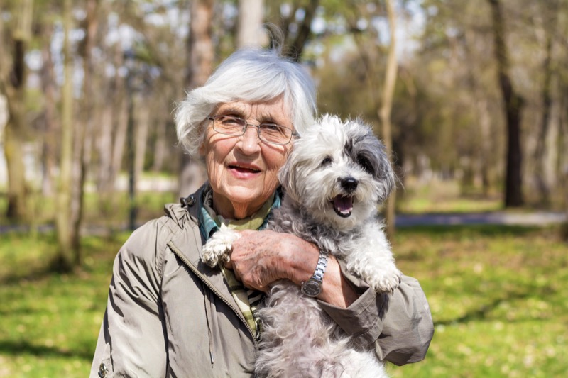beautiful happy senior woman hugging her cute dog outdoor