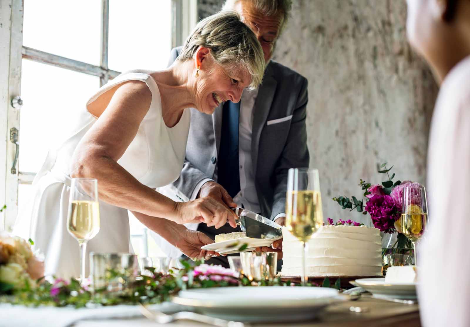 senior couple hands cutting wedding cake