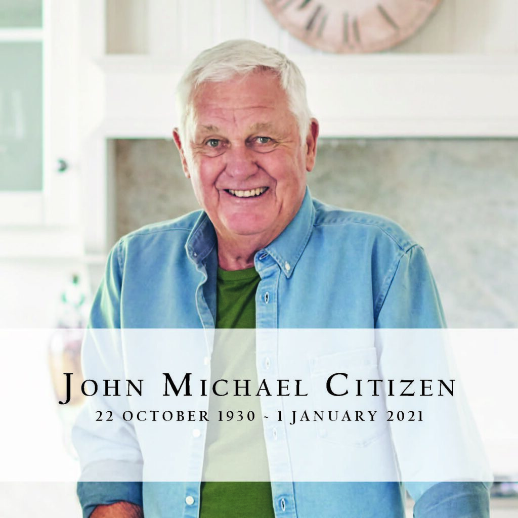 Older man smiling in a kitchen setting.