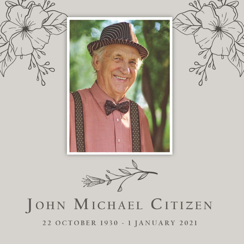 Older man in hat and bow tie smiling outdoors.